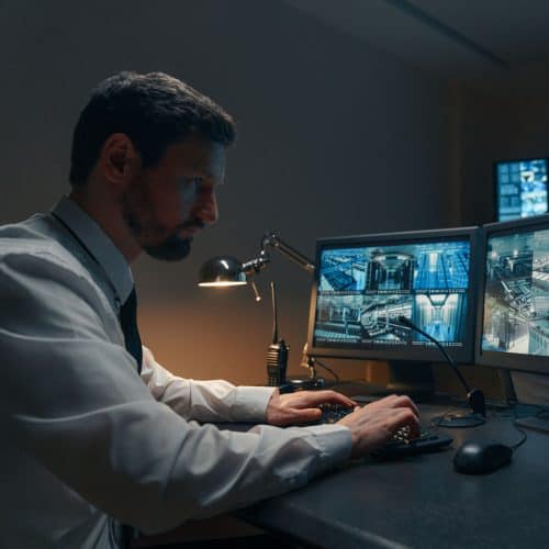 Man at desk looking at many computer screens